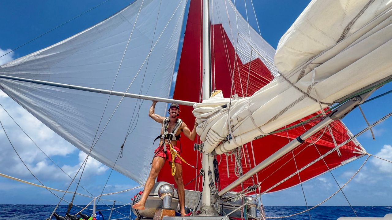 Xander on his sailboat adjusting sails while underway at sea
