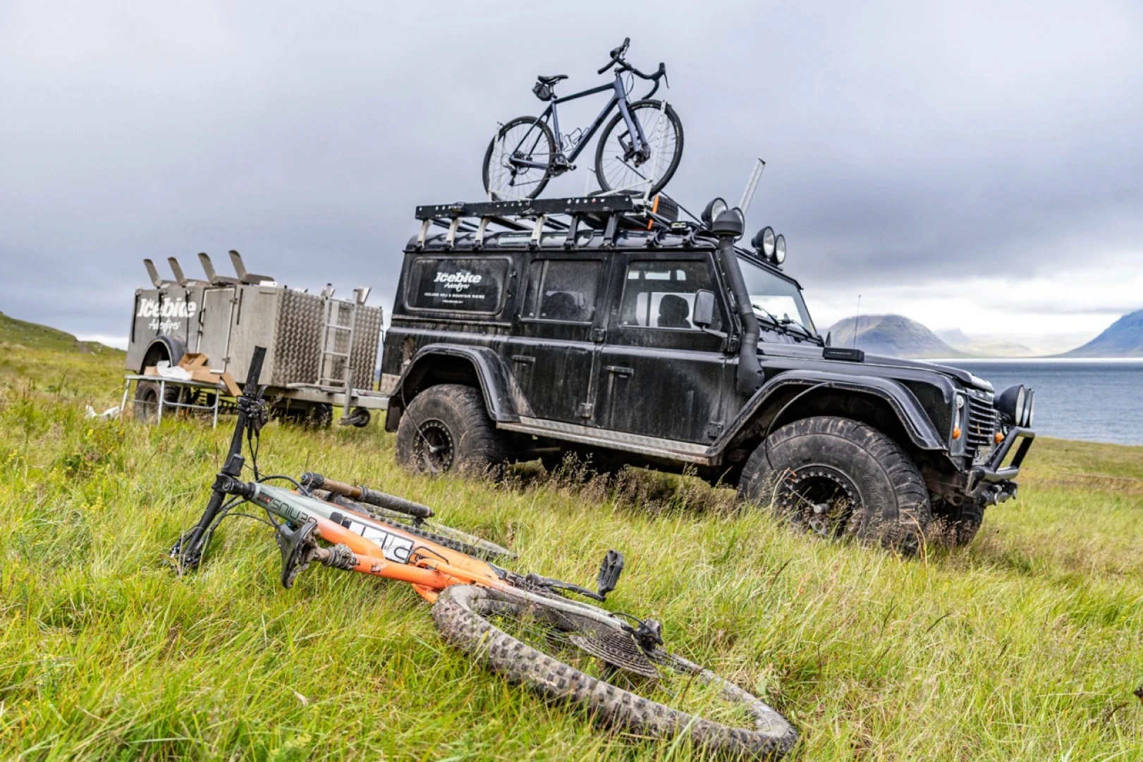 Bike in foreground landrover with bike on top and biketrailer in backround