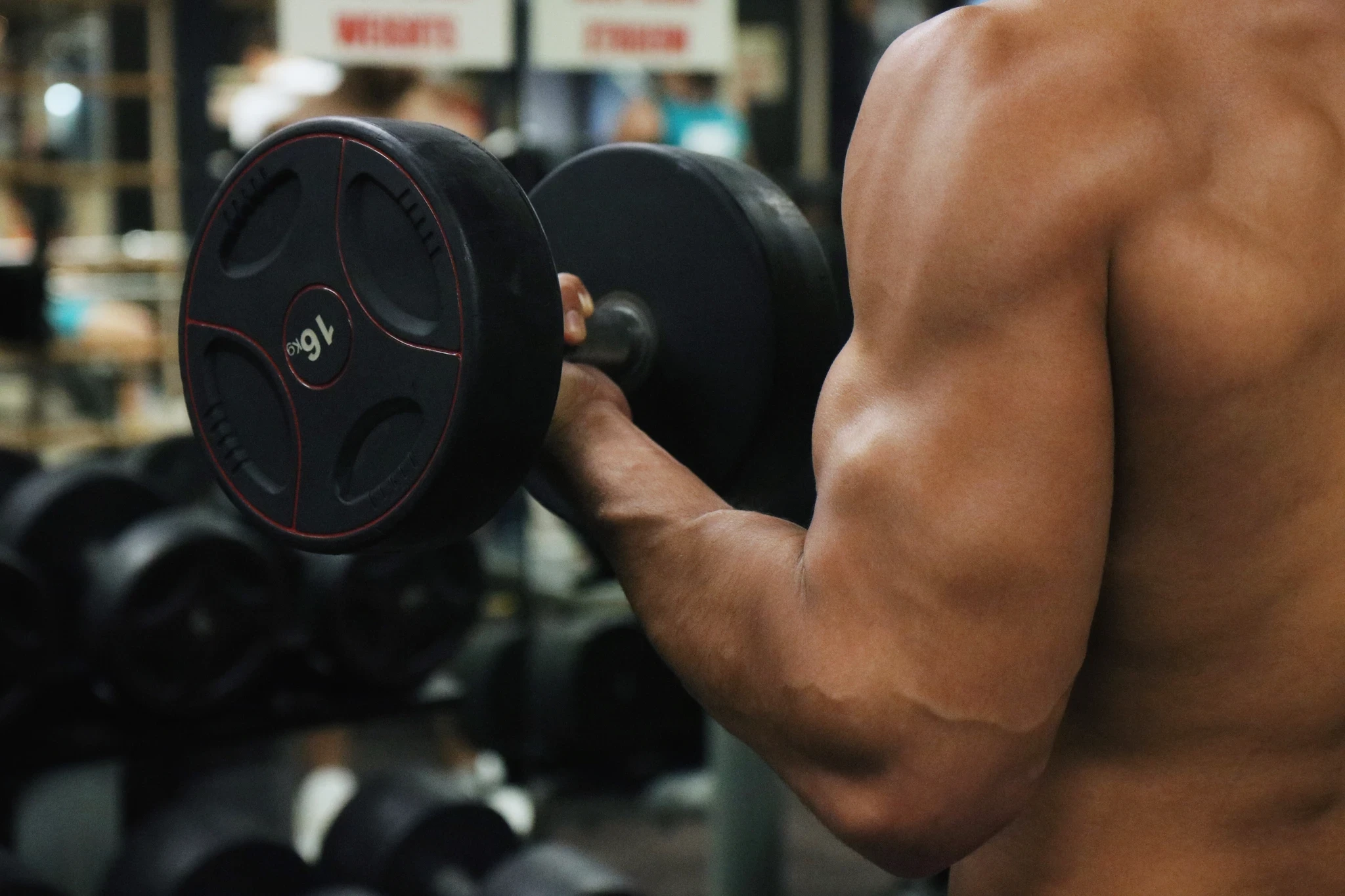 A close-up image of a muscular arm performing a bicep curl, showcasing the definition and strength of the bicep as the person lifts the weight.