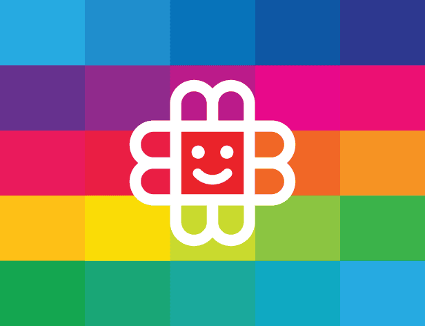 A white stylized flower shape with a smiling face is centered on a rainbow-colored flag. The flag consists of alternating horizontal stripes of blue, cyan, magenta, pink, orange, red, yellow, green, and blue. The flower has four rounded petals and a square center containing the face.