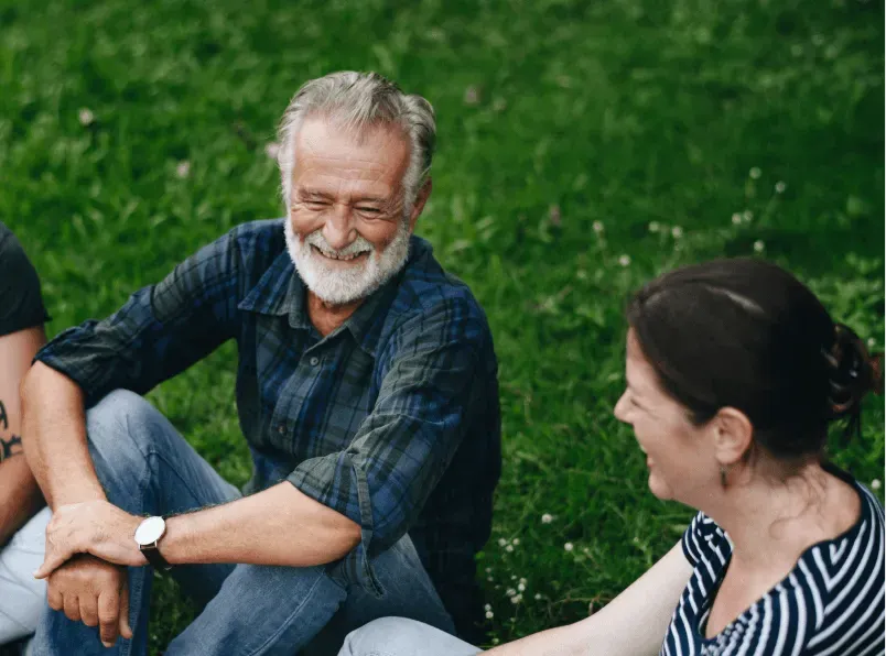 Two people laughing together on a grassy lawn.