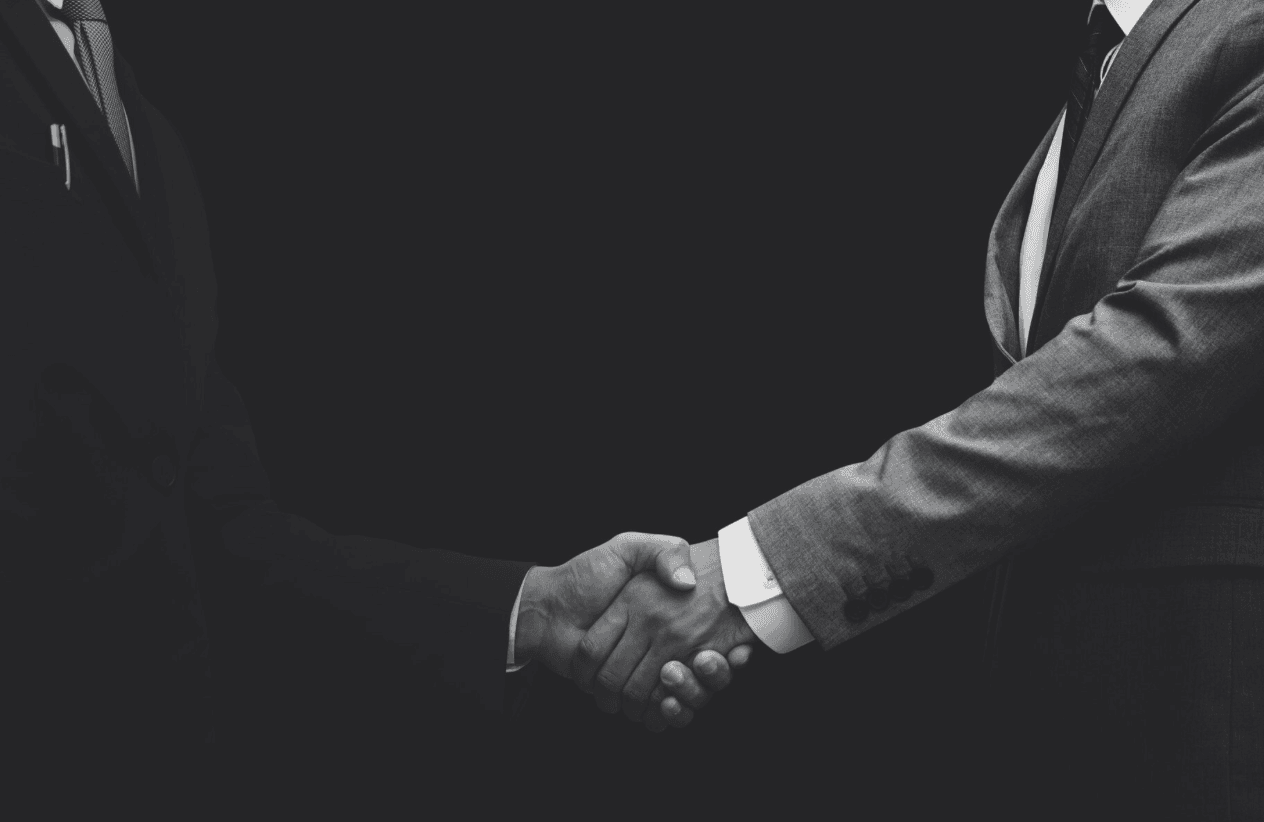 a couple of men shaking hands over a desk