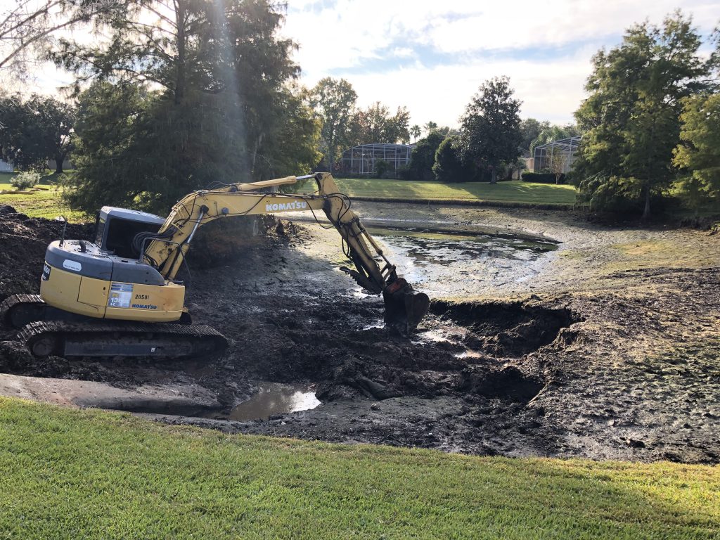 Pond dredging equipment removing muck and hauling off sediment during restoration work.