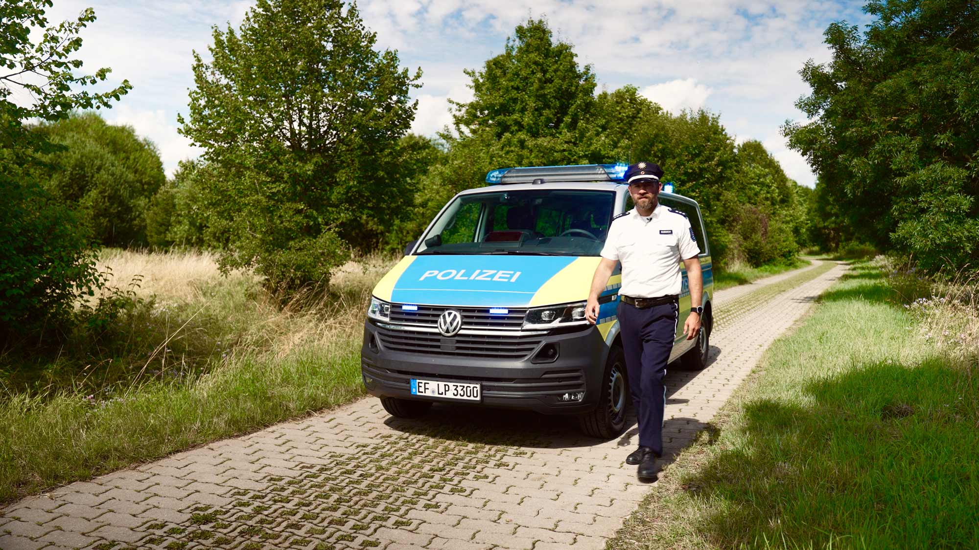 Police vehicle on rural path amid lush greenery, for Lohnt-Sich!-Social-Media-Campaign