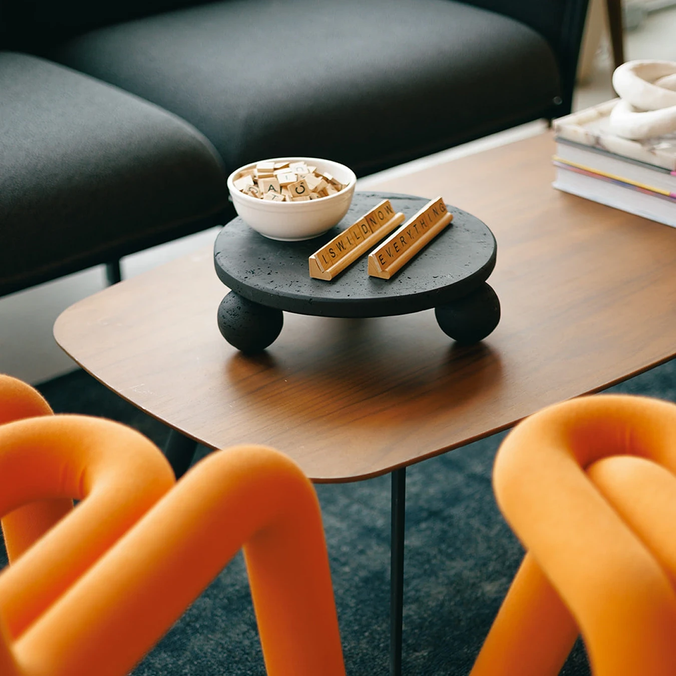 Office coffee table with a bowl of Scrabble tiles and two tile holders spelling "IS WILD NOW" and "EVERYTHING"
