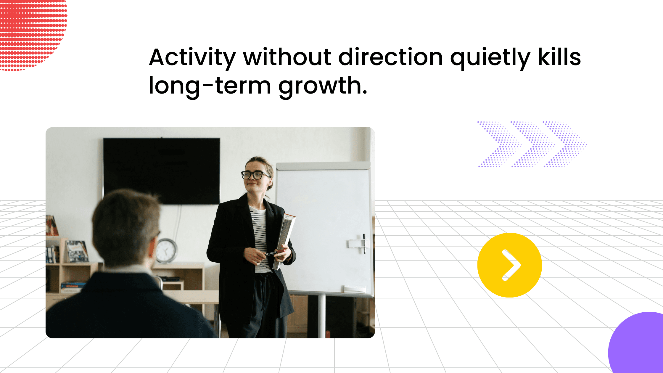 Presenter standing near a whiteboard addressing a seated participant in a training room.