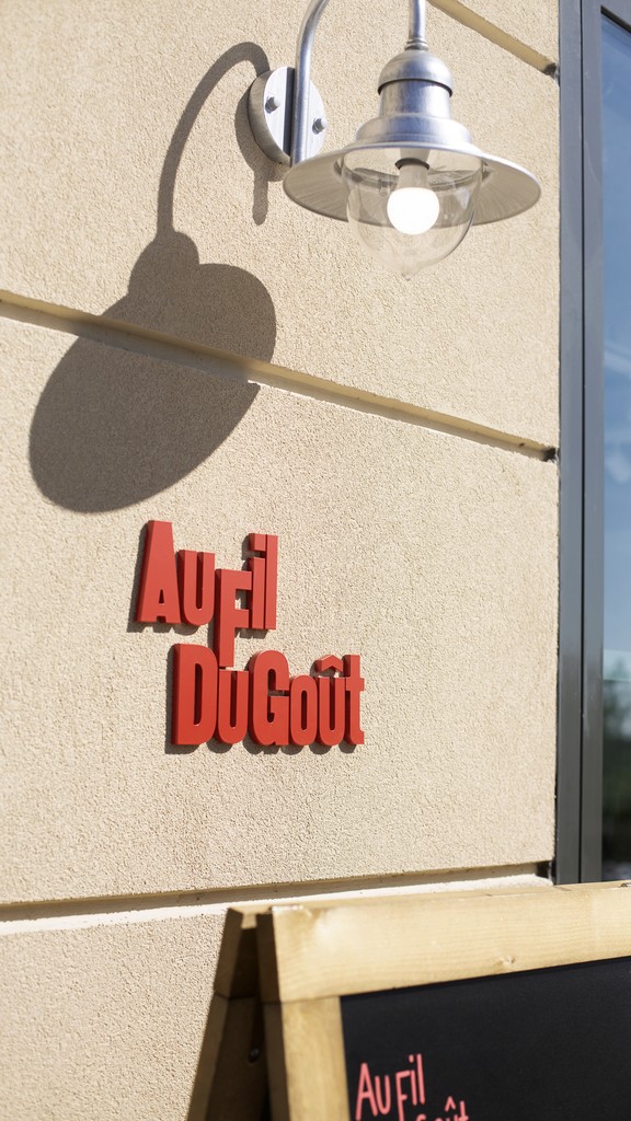 Signalétique extérieure du restaurant Au fil du goût, alliant visibilité et identité graphique forte. Composition graphique moderne pour une communication claire et attractive.