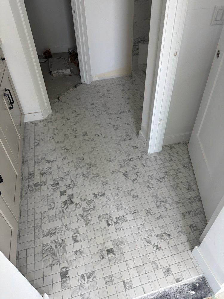 Modern bathroom hallway with marble mosaic tile flooring and white doors in a new home under construction.