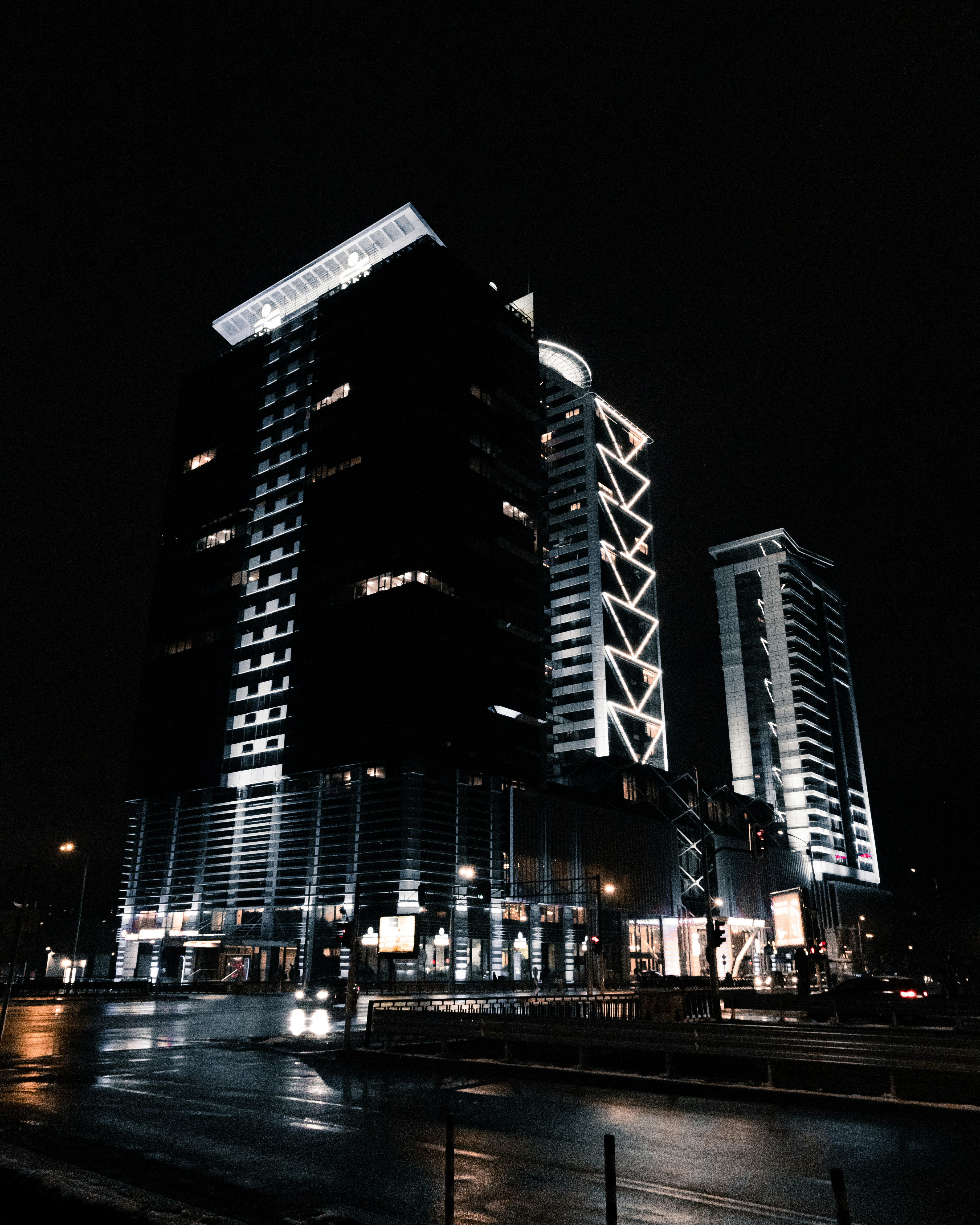 Modern professional service buildings at night in Perth, with vehicles driving by and bright lamps.
