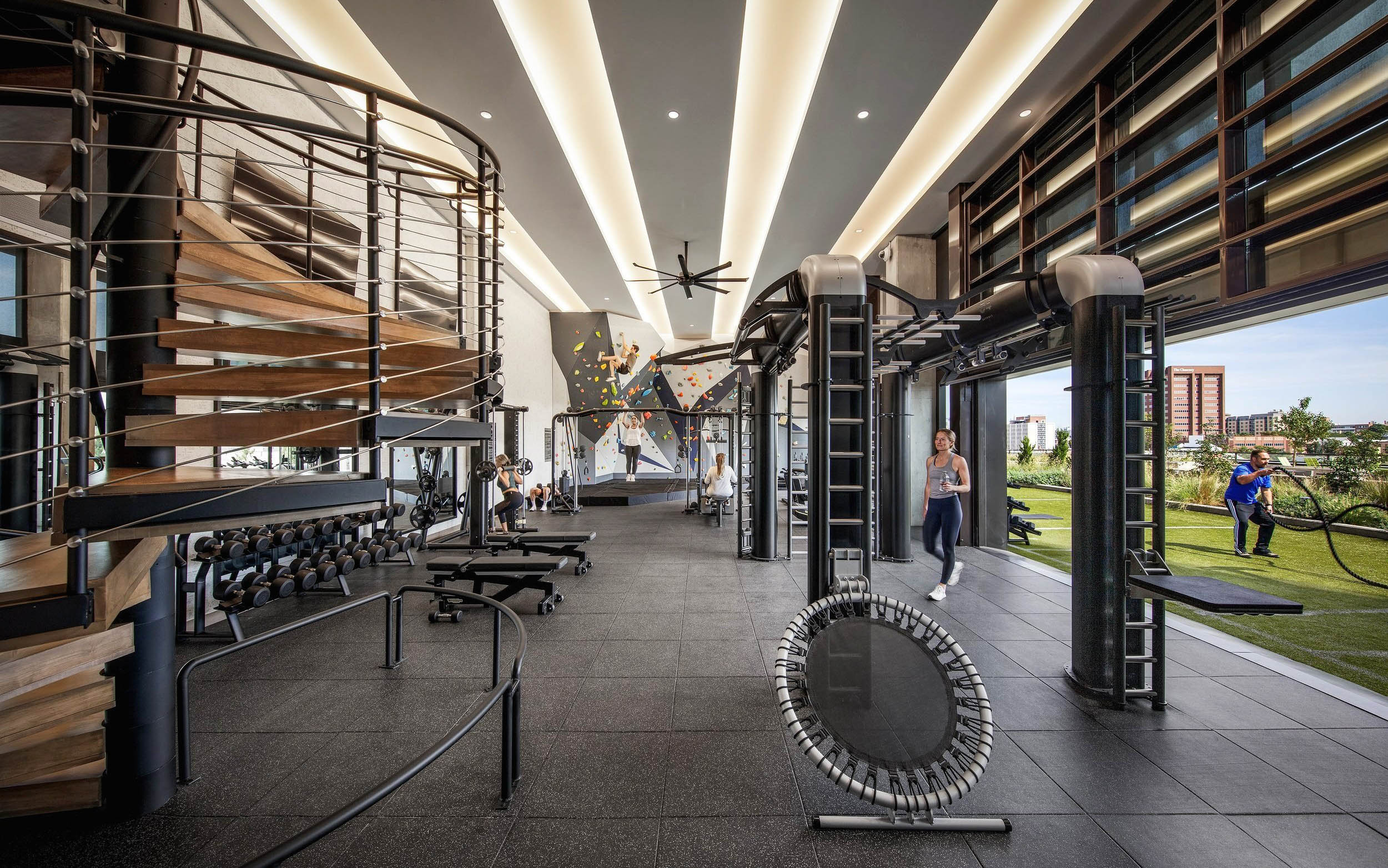 Gym with climbing wall, weights, and outdoor turf area.