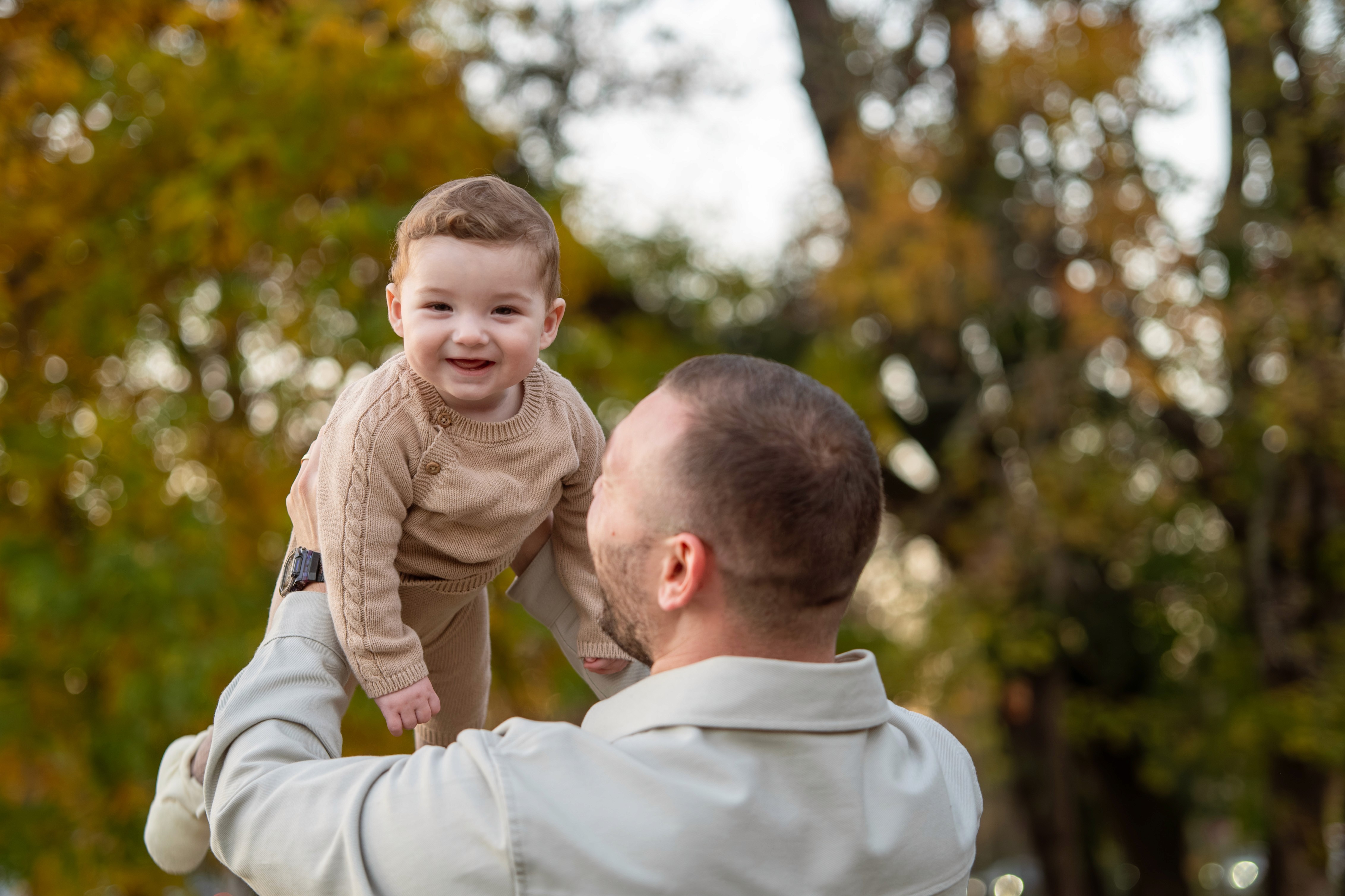 Moment emoțional din ședință foto de familie în București, tată și copil jucându-se în parc.