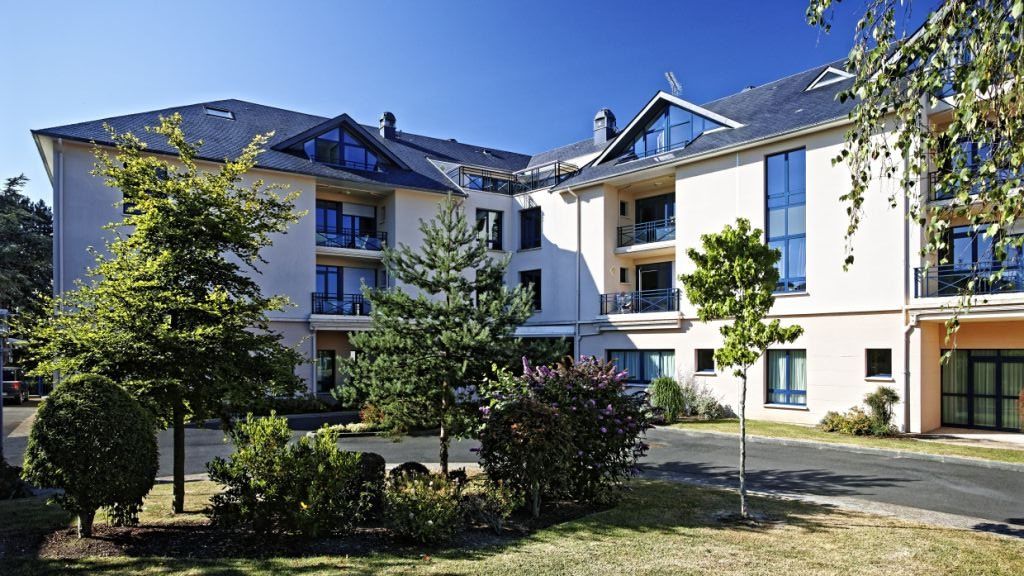 Modern residential building with multiple floors balconies and landscaped grounds in coastal setting