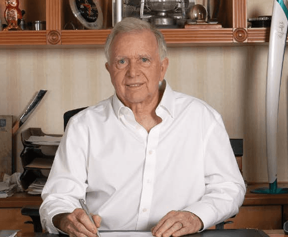 a man in a blue shirt smiling at the camera