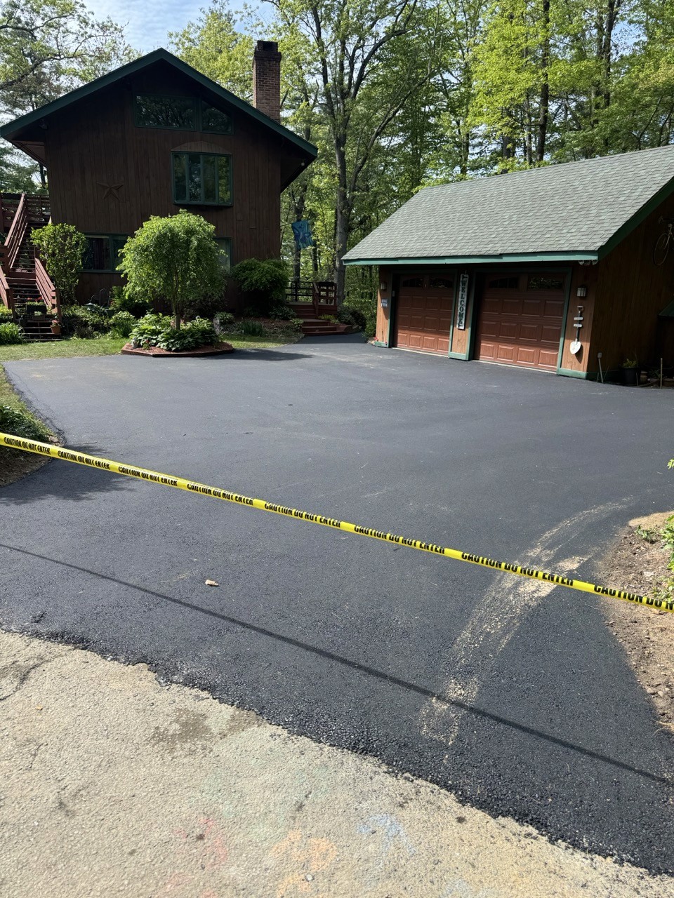Fresh asphalt driveway beside a log home and garage, by A&M Construction Enterprises