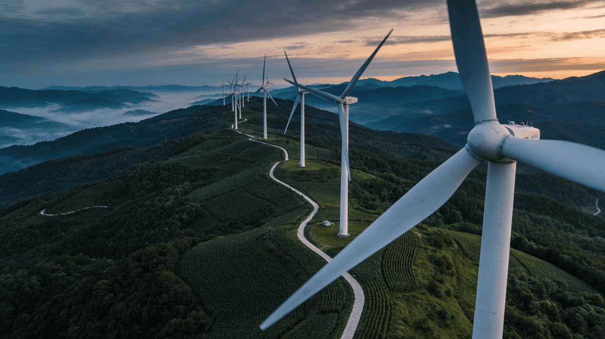 A rustic kitchen scene featuring glass jars of sourdough starter on a wooden table, with a notebook filled with handwritten recipes, a brown bowl of flour, and a beige fabric apron, illuminated by soft natural light from a window.