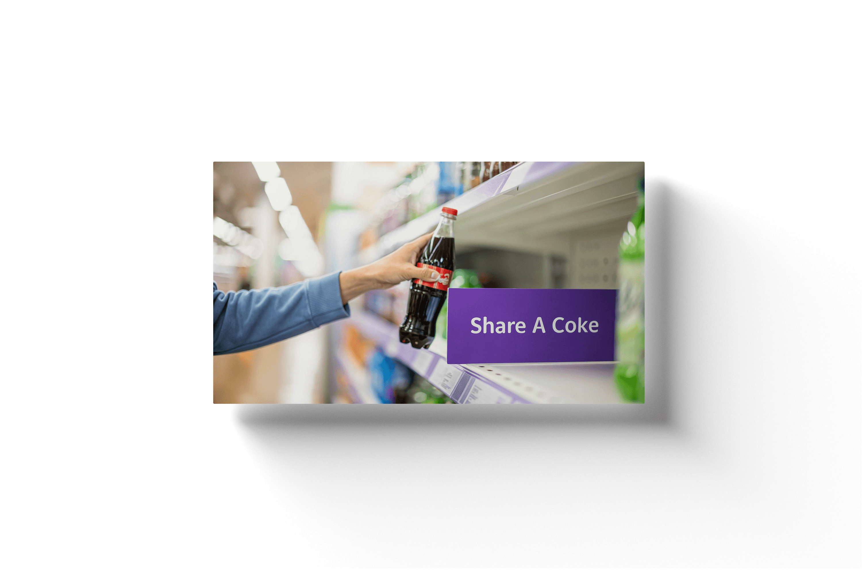 a person grabbing a glass soda bottle off of a shelf with a red label behind a purple shelf divider with 'share a coke' on the side
