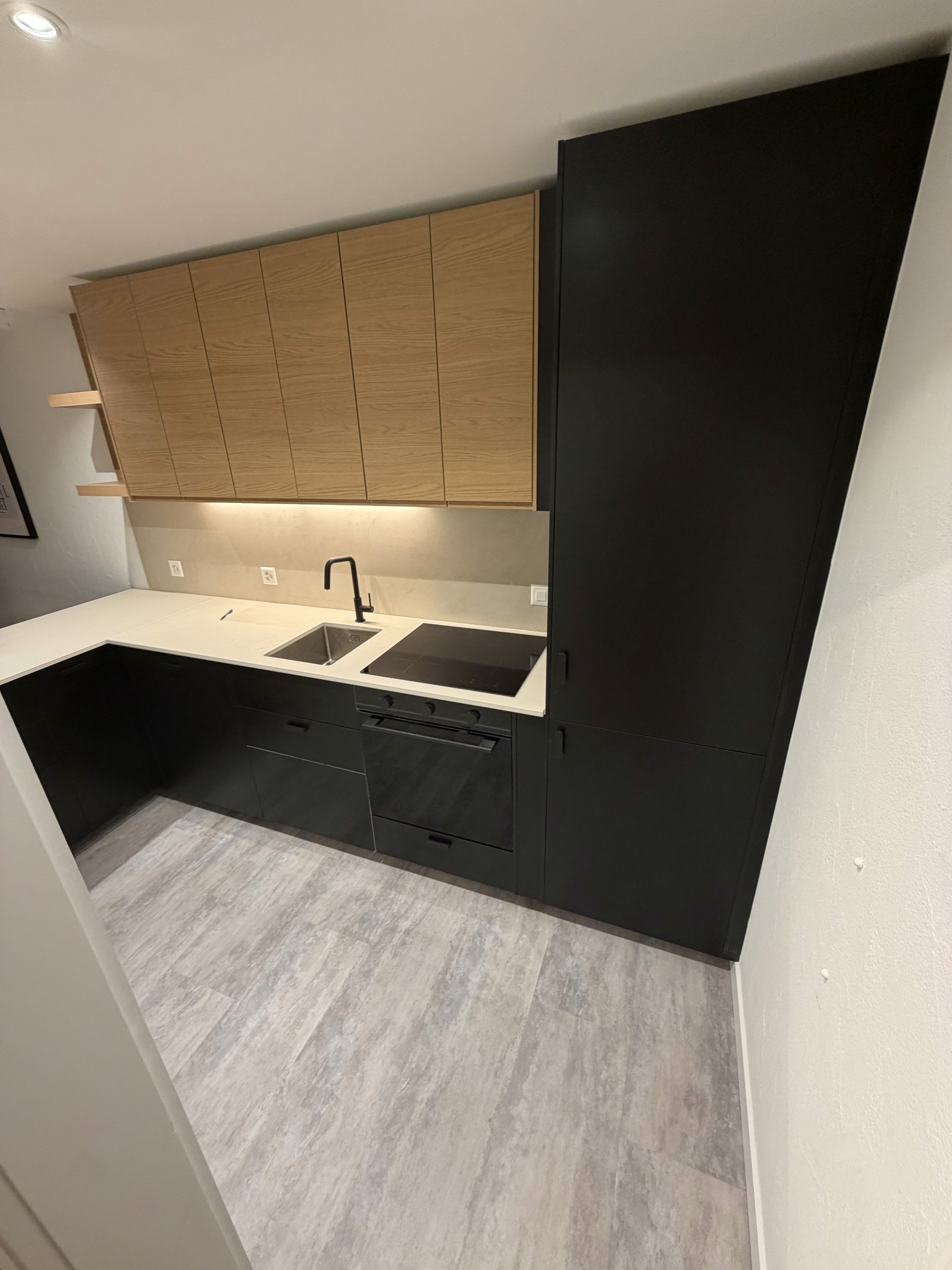 IKEA kitchen with dark base units, timber-look wall cabinets and a light worktop