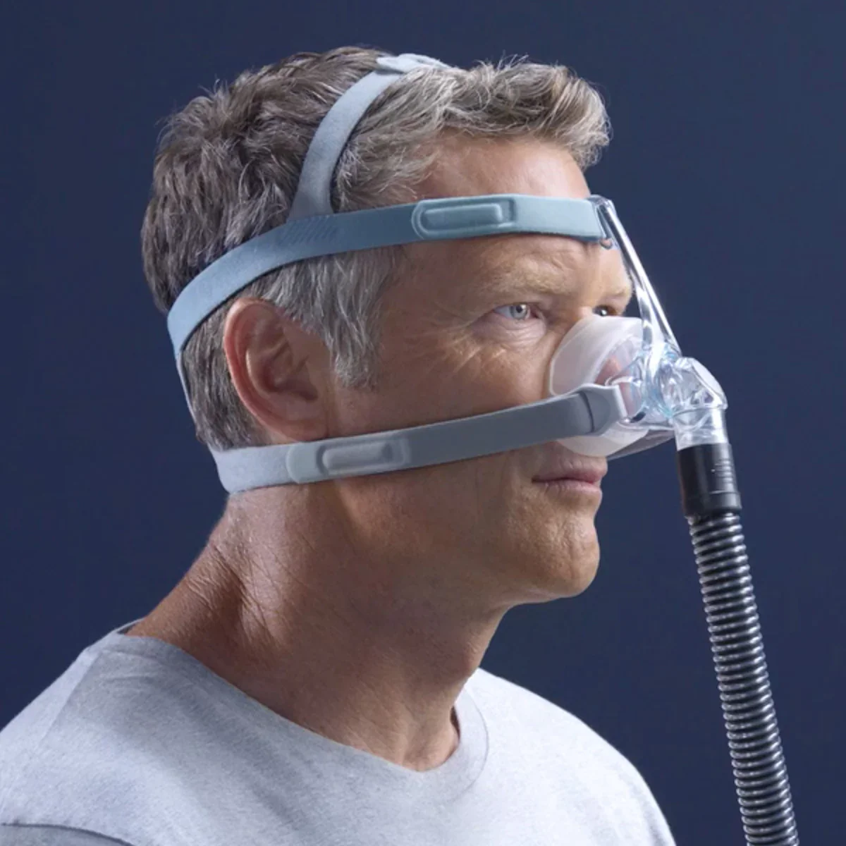 A middle aged male is side on wearing a nasal CPAP mask.