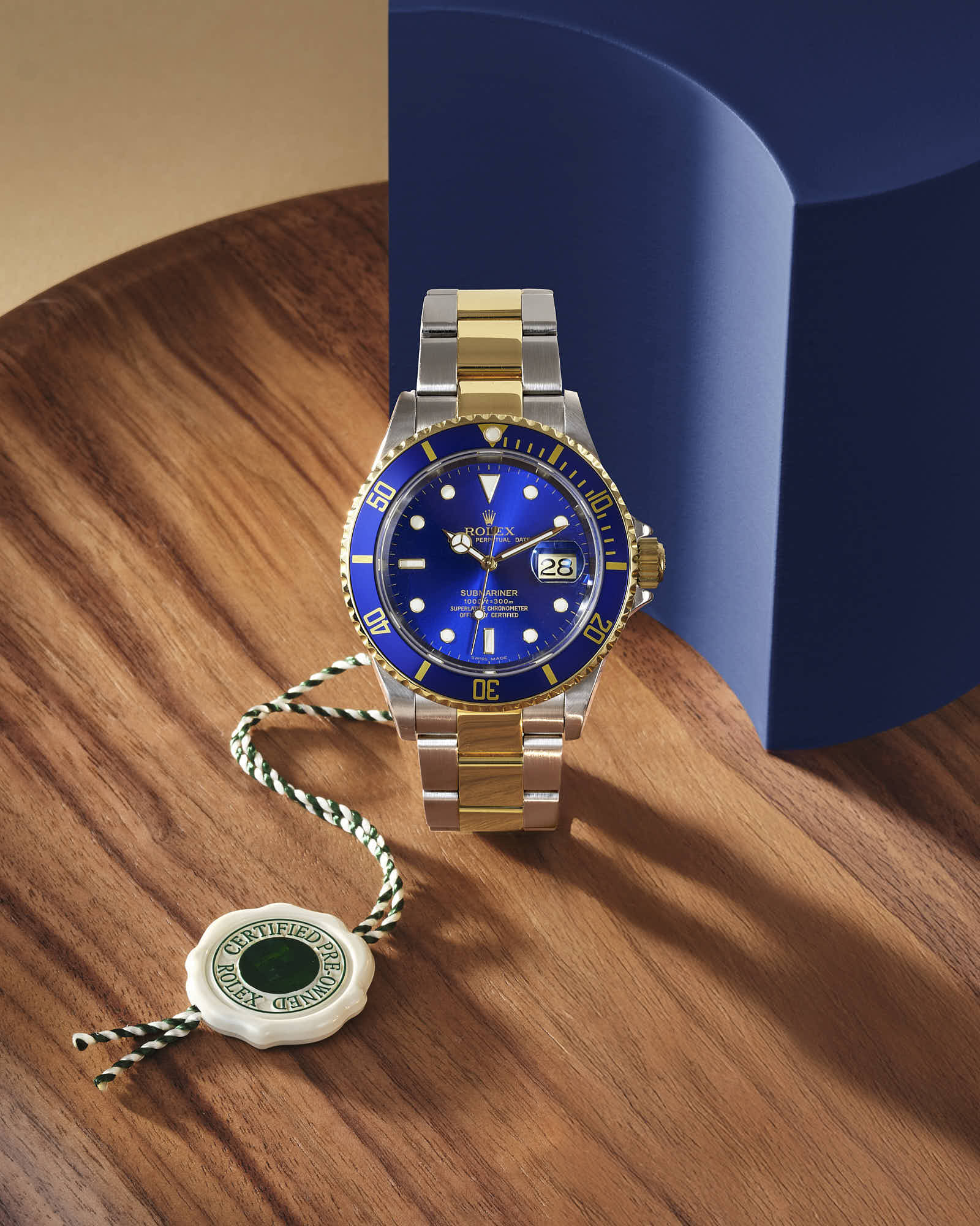 Luxury gold and silver Rolex watch with blue dial on a wooden surface.