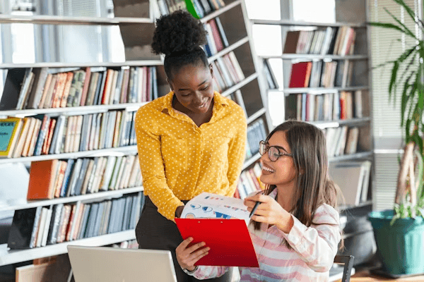 High school student conducting original literature research with a PhD mentor in a university library setting