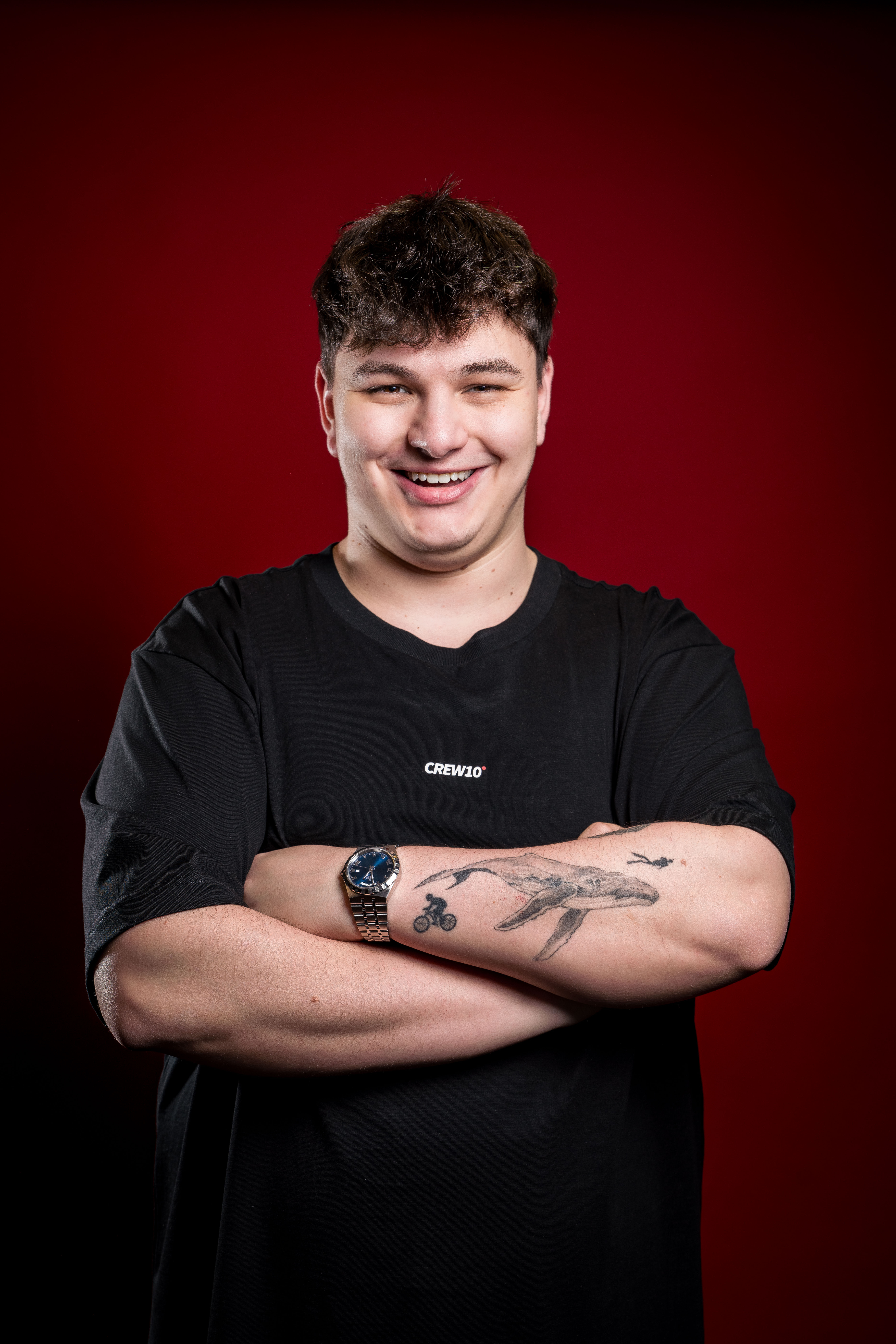 A smiling man in a suit and glasses sits at a table, with a modern office backdrop.