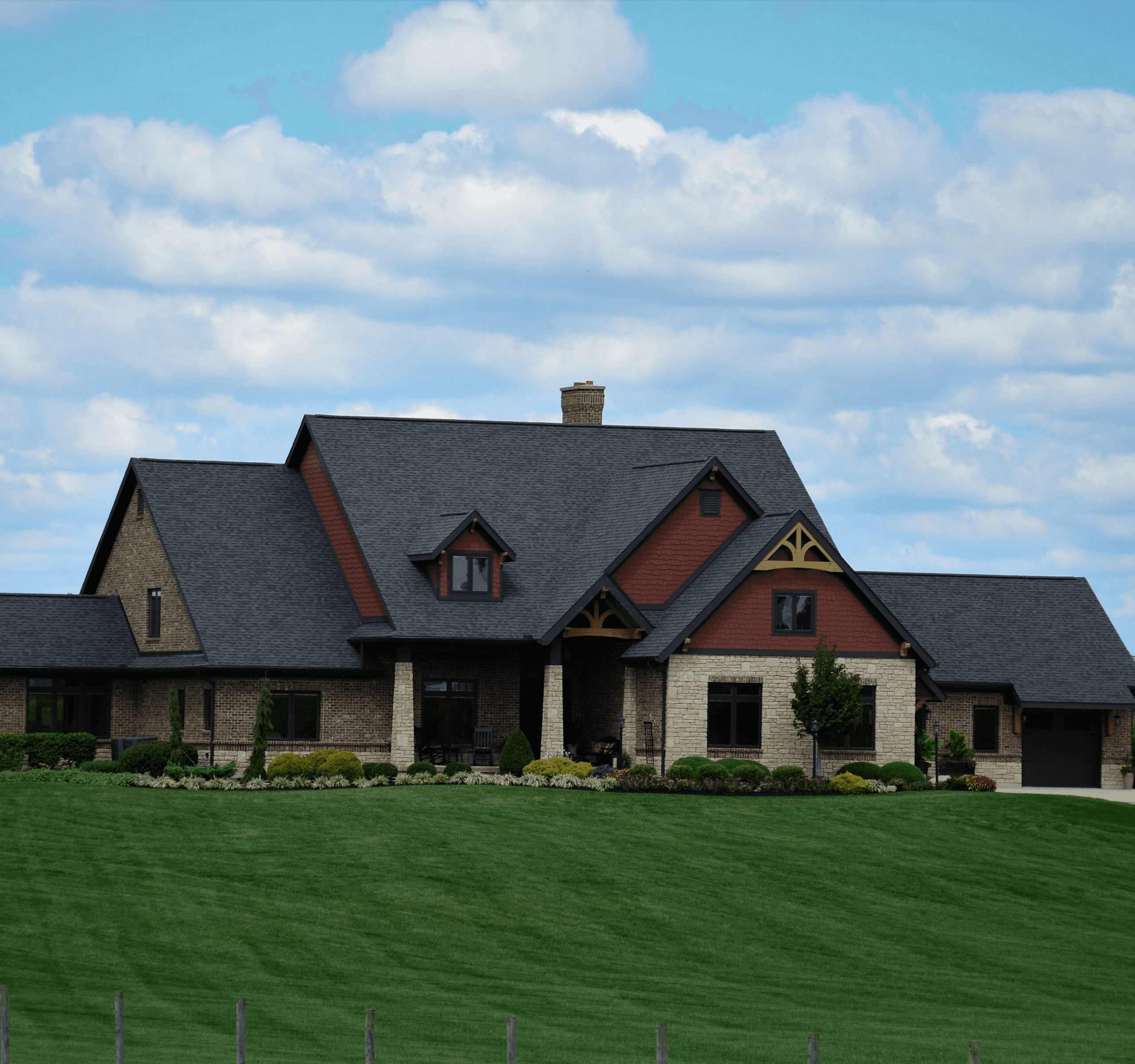 A modern house with a large lawn and a partly cloudy sky.