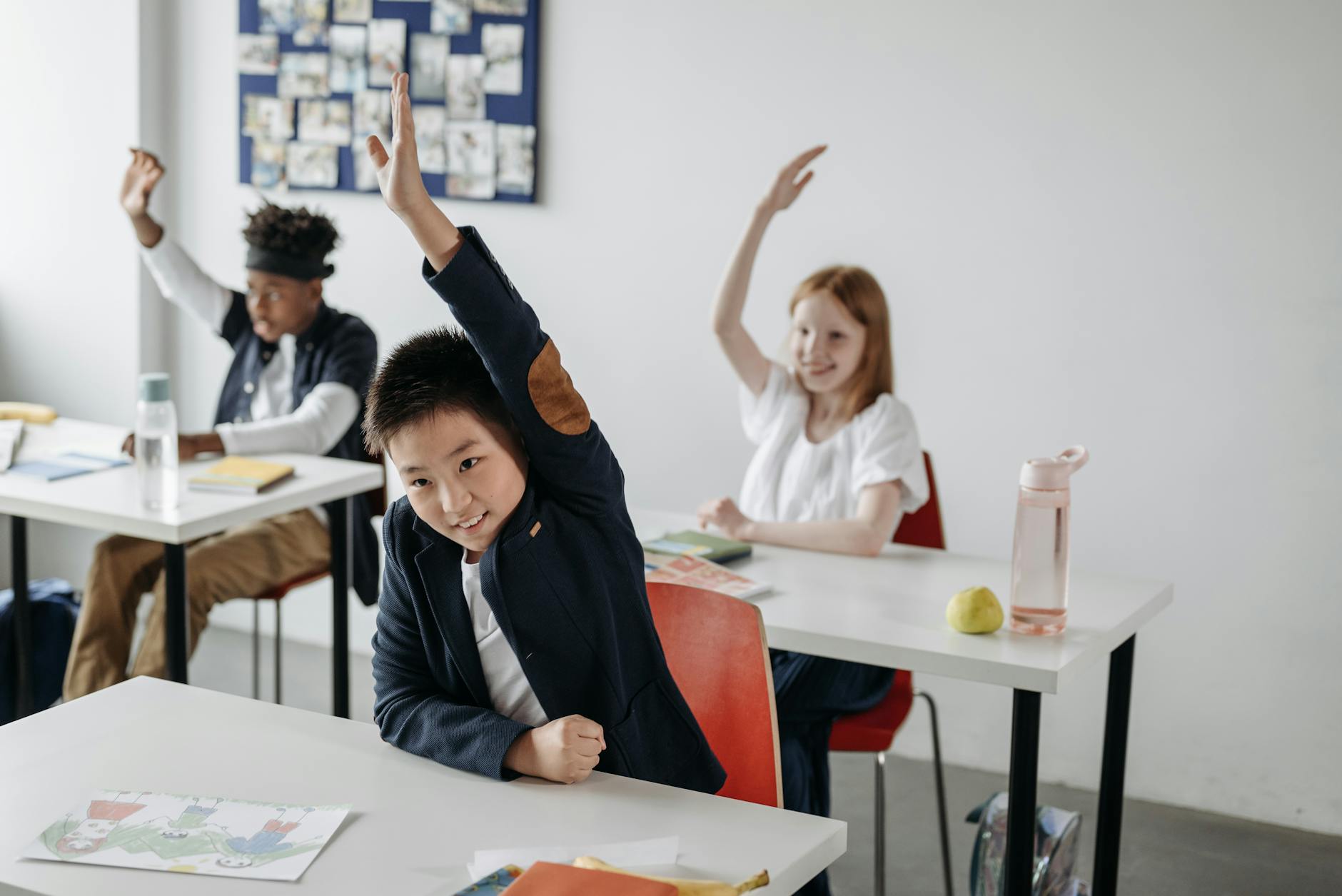 A teacher standing at a whiteboard leading a lively group discussion with diverse high school students.
