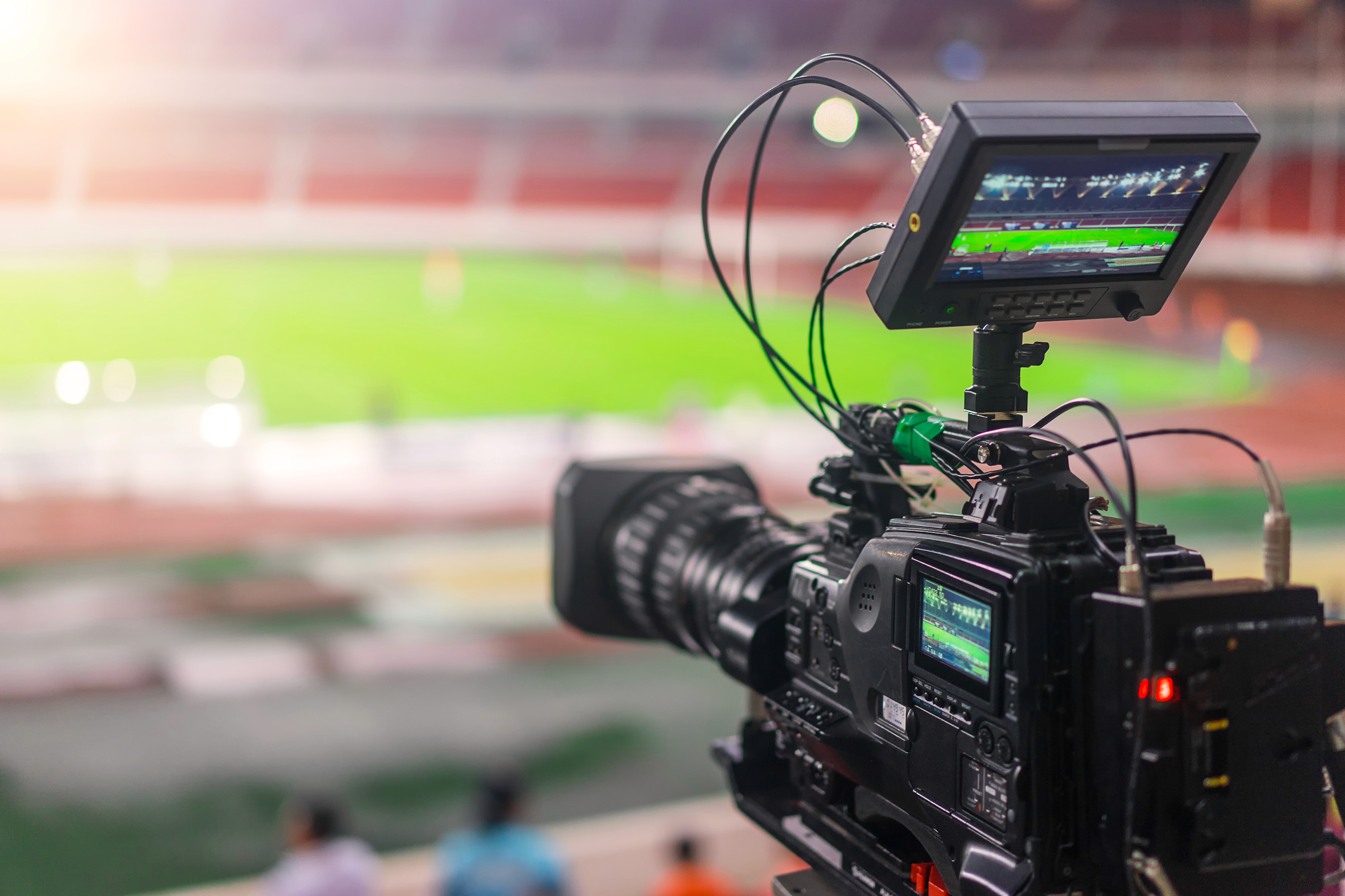 A professional 4K broadcasting camera filming a live football match in a stadium. This visual represents Woody Technologies' commitment to providing enterprise-grade solutions like Woody Vision for real-time sports broadcasting and live event media management.