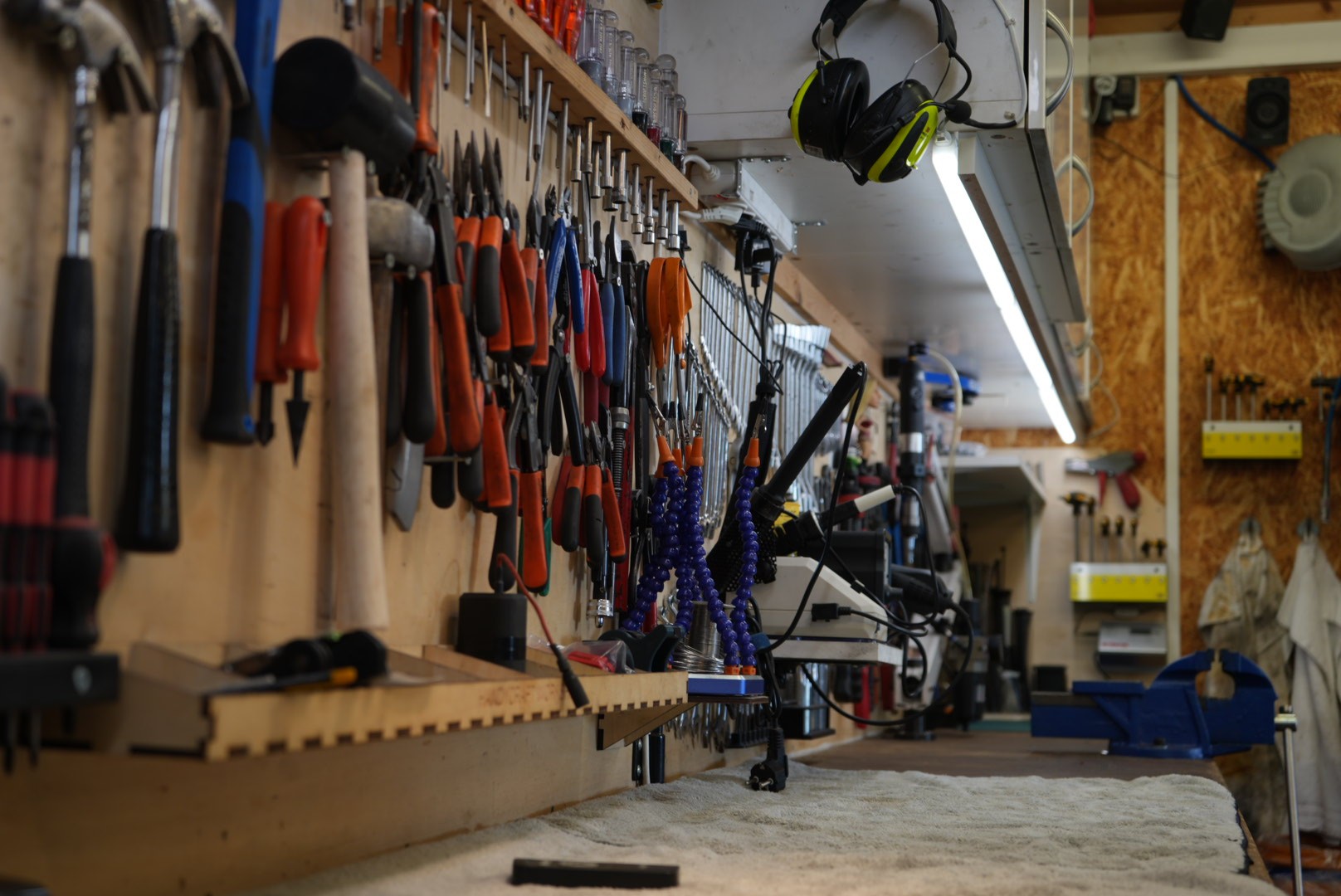 Close-up of a modern building facade featuring vertical wooden panels and black-framed windows, with natural light casting tree shadows on the surfaces.