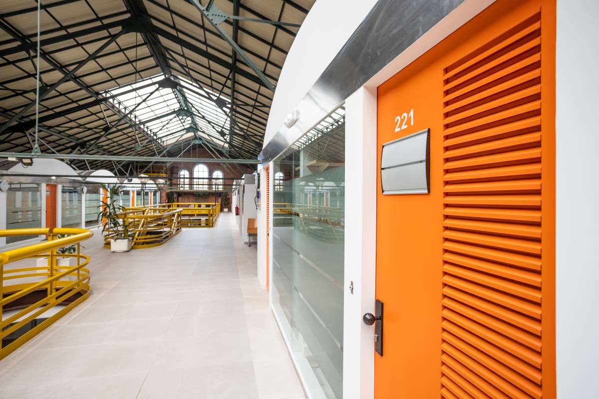 Work meeting where a guy in casual clothing is leading the meeting with other sat down and listening