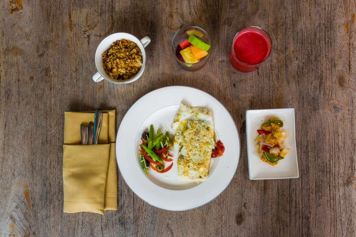 Top-down view of a table set with a large plate of grilled fish and vegetables, small side dishes, and two drinks.