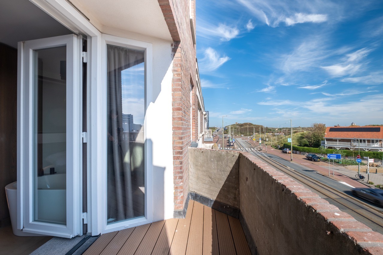 Privébalkon van Suite 1 met uitzicht op de straat en helderblauwe lucht