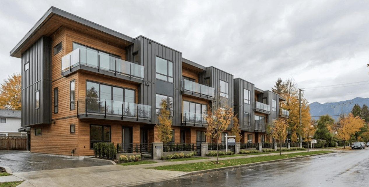 First-person perspective standing on townhouse rooftop deck with frameless glass railings wrapping the perimeter, downtown Vancouver skyline in background, dramatic clouds, wide angle lens, glass so clear it nearly disappears, emphasis on unobstructed 180-degree views, lifestyle real estate photography
