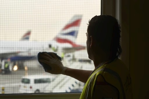 A group of construction workers wearing high-visibility jackets and hard hats celebrate at a construction site with safety signs and equipment visible in the background.
