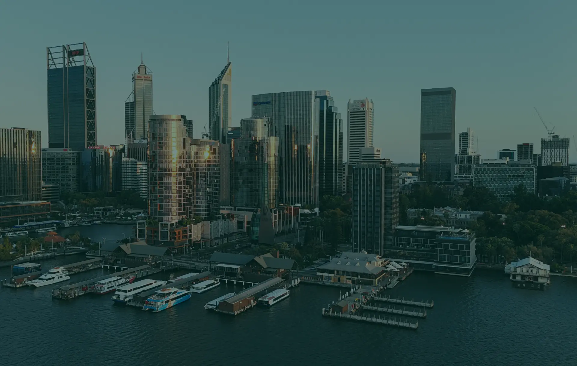 City skyline with waterfront buildings and boats at dusk