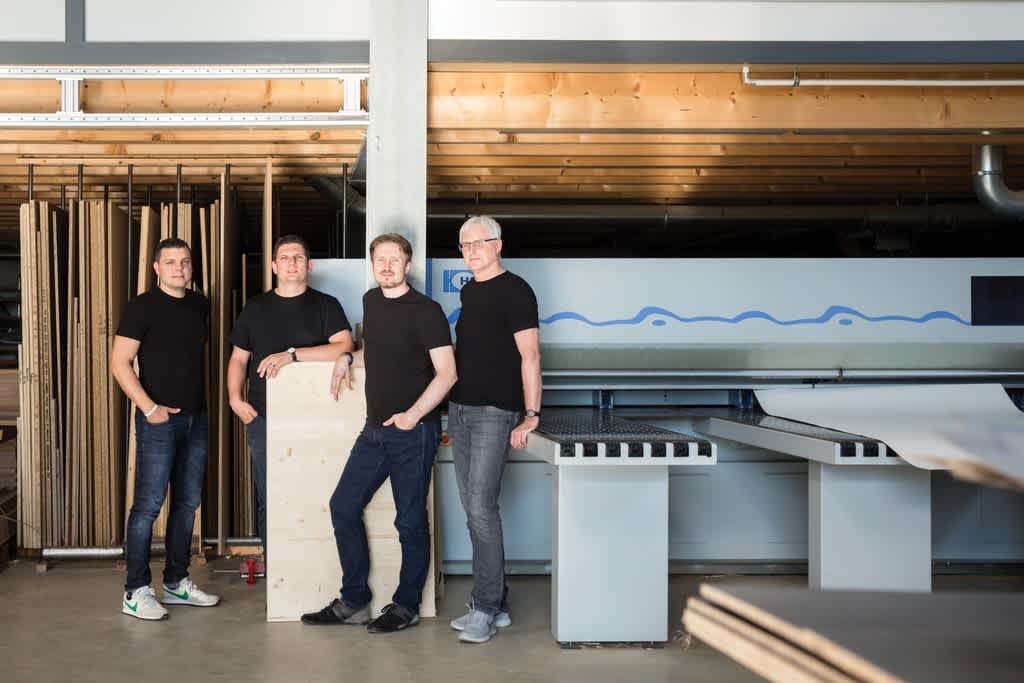 4 people in black T-shirts in front of a HOMAG machine