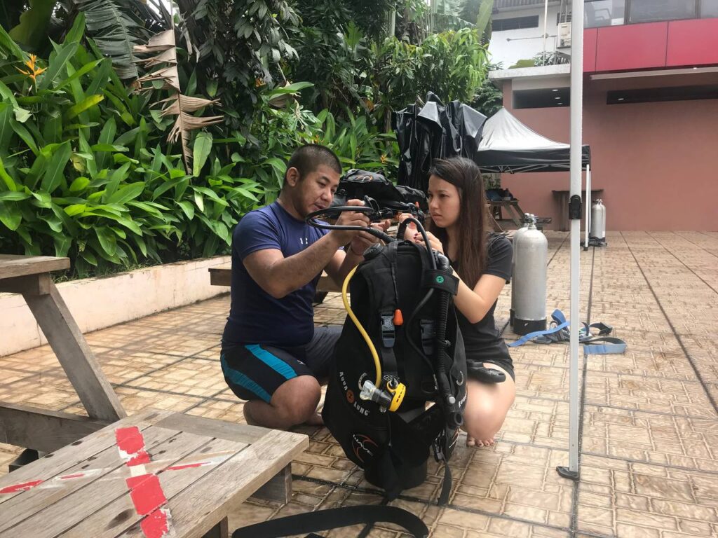 Sea Familia Dive Academy instructor fitting a student's BCD during a course introduction