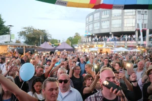 Publikum bei Tageslicht mit erhobenen Händen, ein Luftballon über der Menge.
