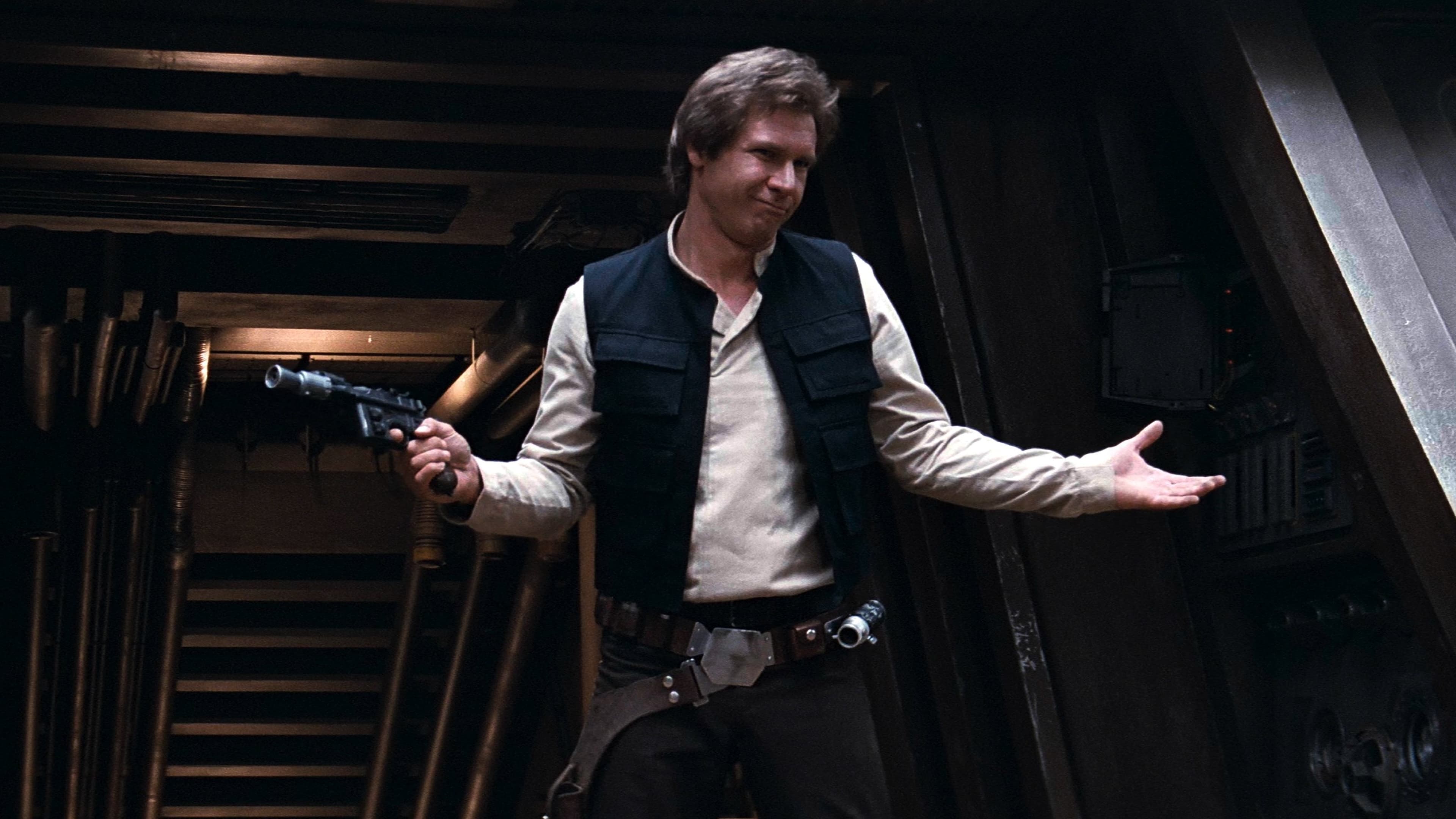 A person in a white shirt and black vest stands confidently in a dimly lit spaceship corridor, holding a blaster in one hand and gesturing with the other. The background shows pipes and metallic surfaces.