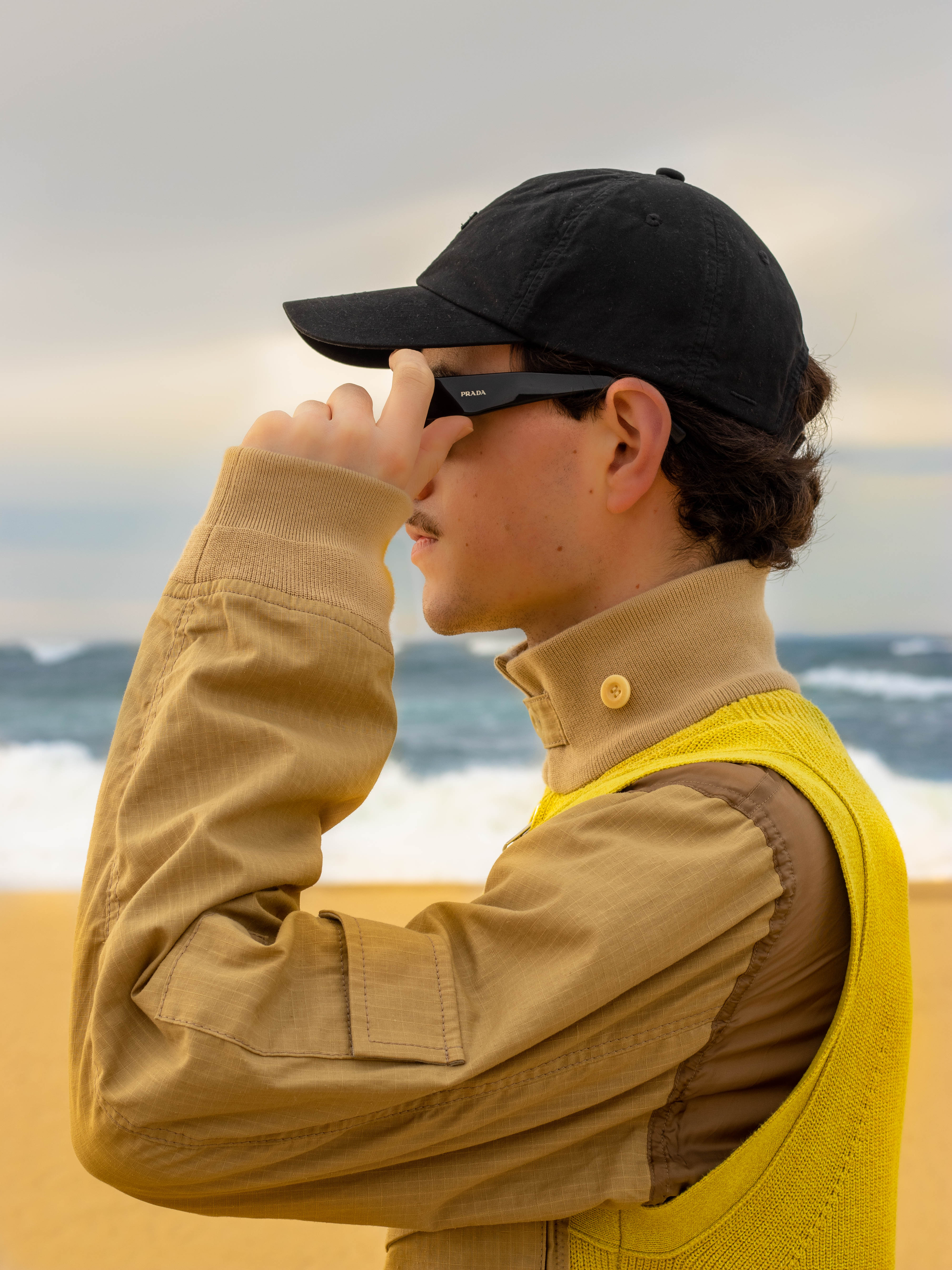 shooting masculin nature proche de l'océan, une tenue jaune très vif qui contraste avec le blue de l'eau