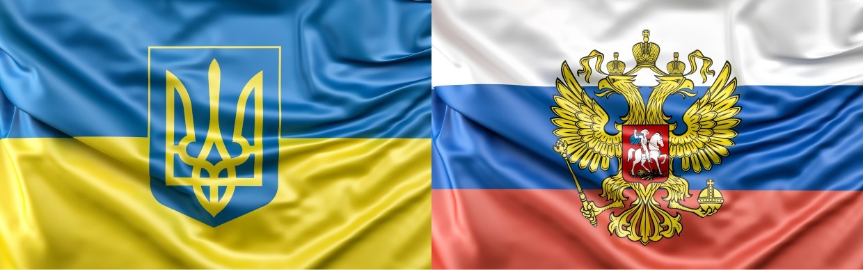 A split-image showing the Ukrainian flag on the left with the national coat of arms, and the Russian flag on the right featuring the double-headed eagle emblem, illustrating rising geopolitical tensions and their impact on sanctions complexity.
