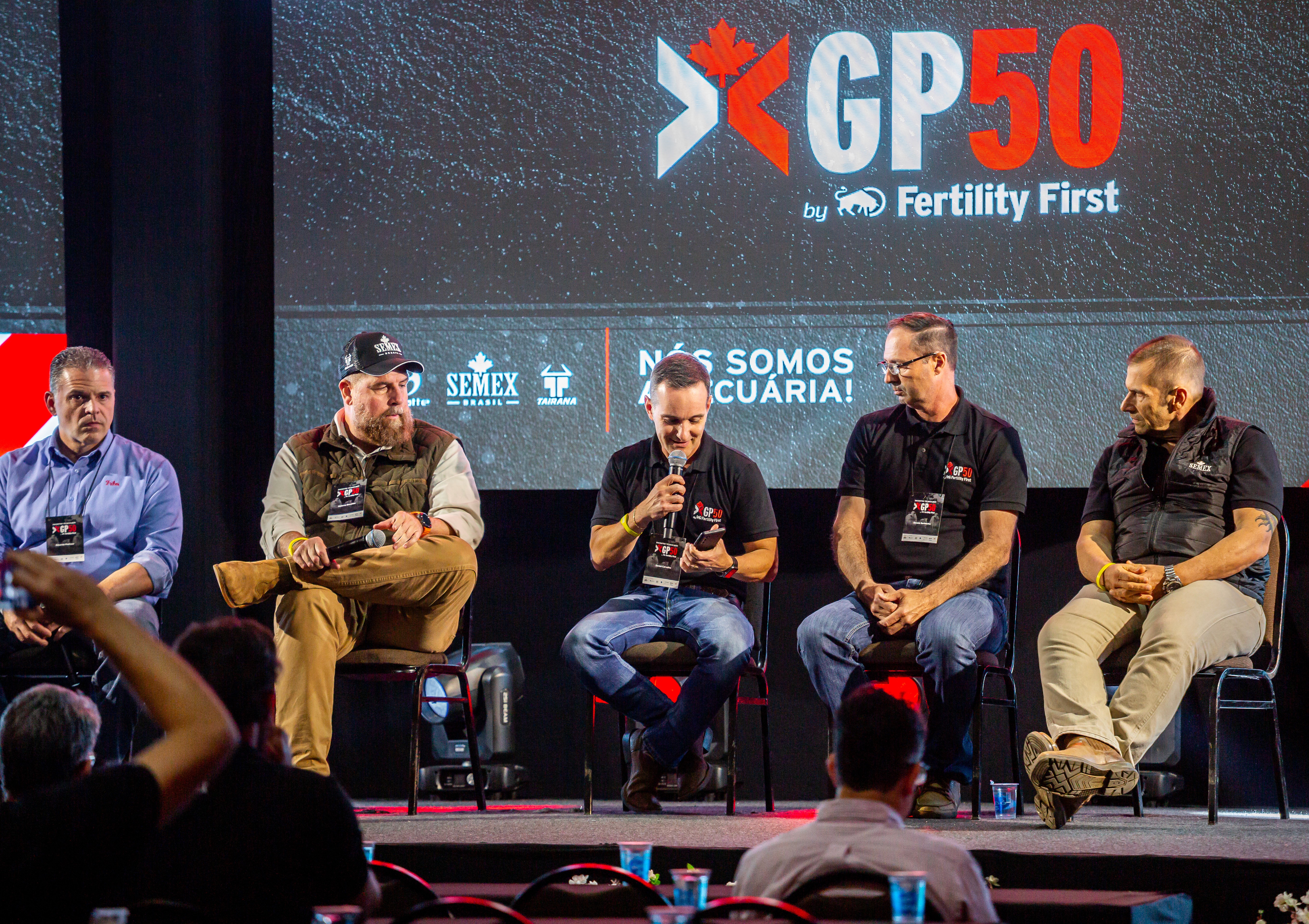person discussing while standing in front of a large screen in front of people inside dim-lighted room