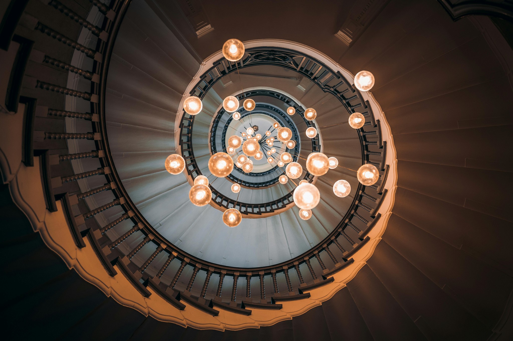 Escalier circulaire avec lustres suspendus dans un hôtel de luxe.