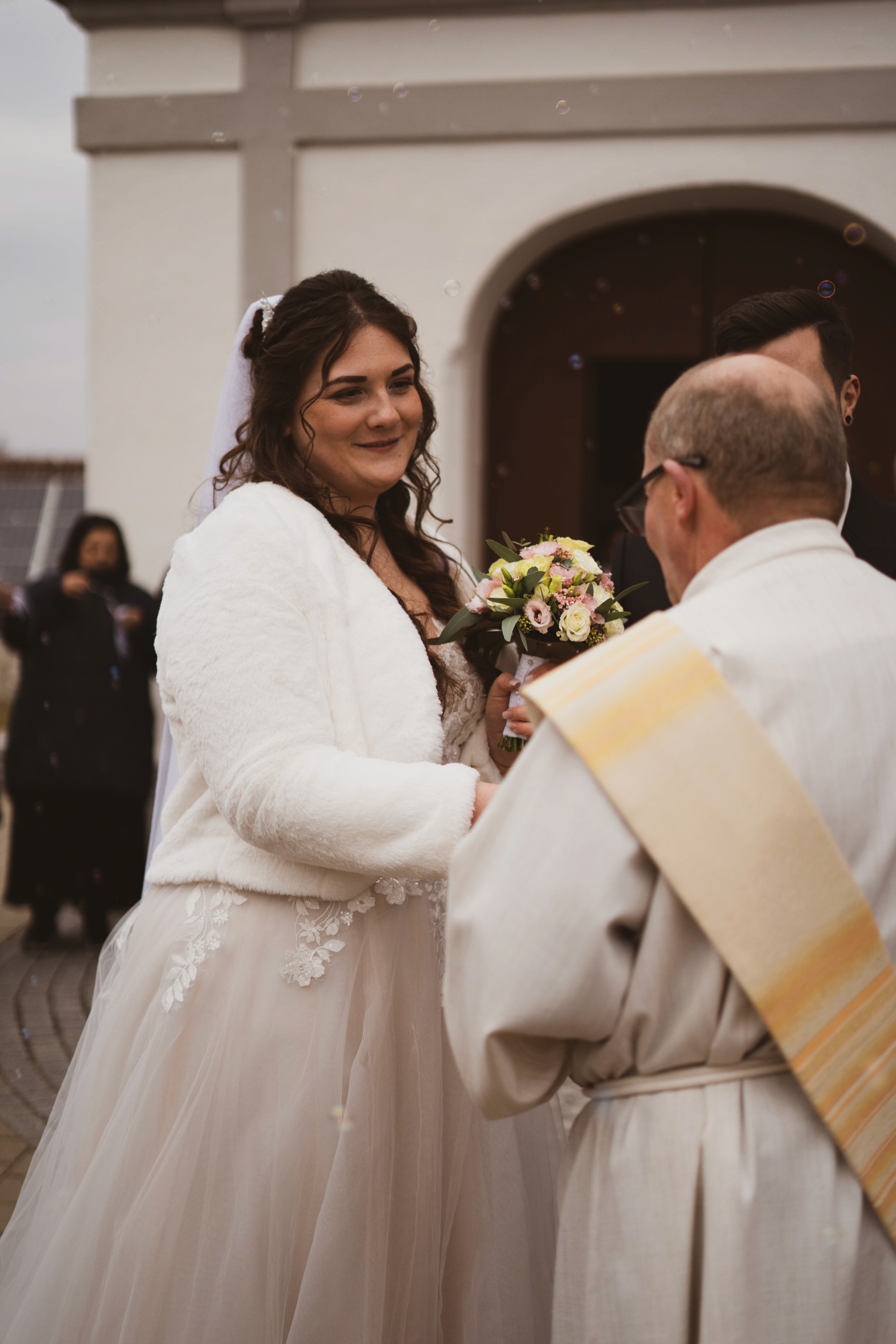 A bride and groom share a kiss surrounded by a joyful bridal party.