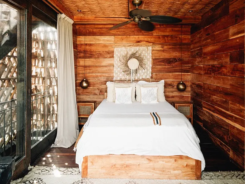 Experience the ultimate in luxury and relaxation with the treehouse suite at Nomade Holbox in Holbox Mexico, featuring a comfortable bed and modern amenities