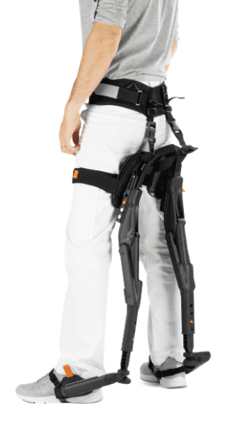 Chairless Chair en position debout, avec le système replié derrière les jambes, prêt à être utilisé comme support d’assise.