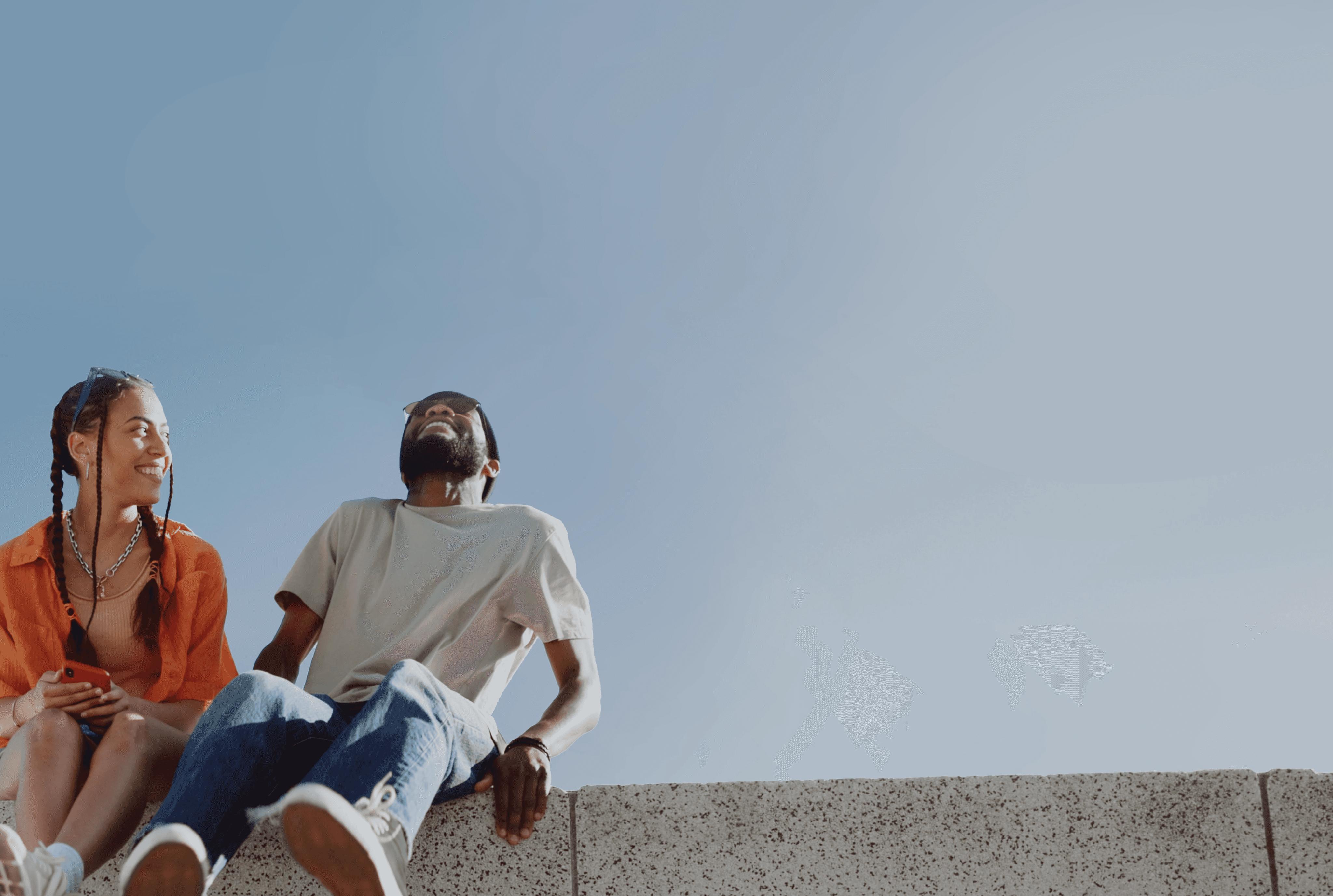 Two people relaxing outdoors and smiling, representing Linqa’s vision of effortless human connection.