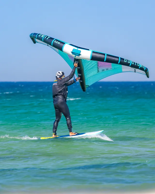 Beginner wing foiler riding on water using handheld wing at Explora Watersports Tarifa