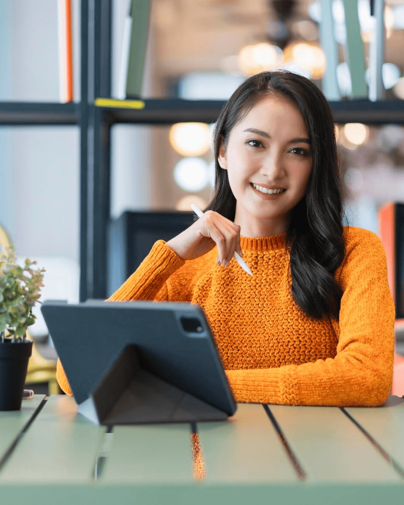 A woman smiling in a professional office workspace with a tablet on her desk.