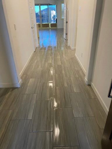 Modern hallway with glossy gray wood-look tile flooring and white walls in a new home under construction.
